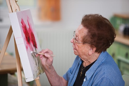 A senior woman enjoying painting in her home