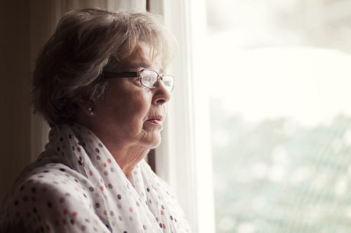 Senior woman waiting by the window for home care provider
