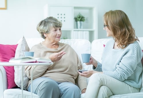 A senior woman having an engaging conversation in her home with a caregiver